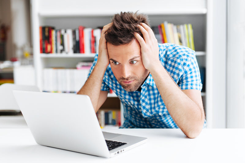 confused man is looking at a laptop